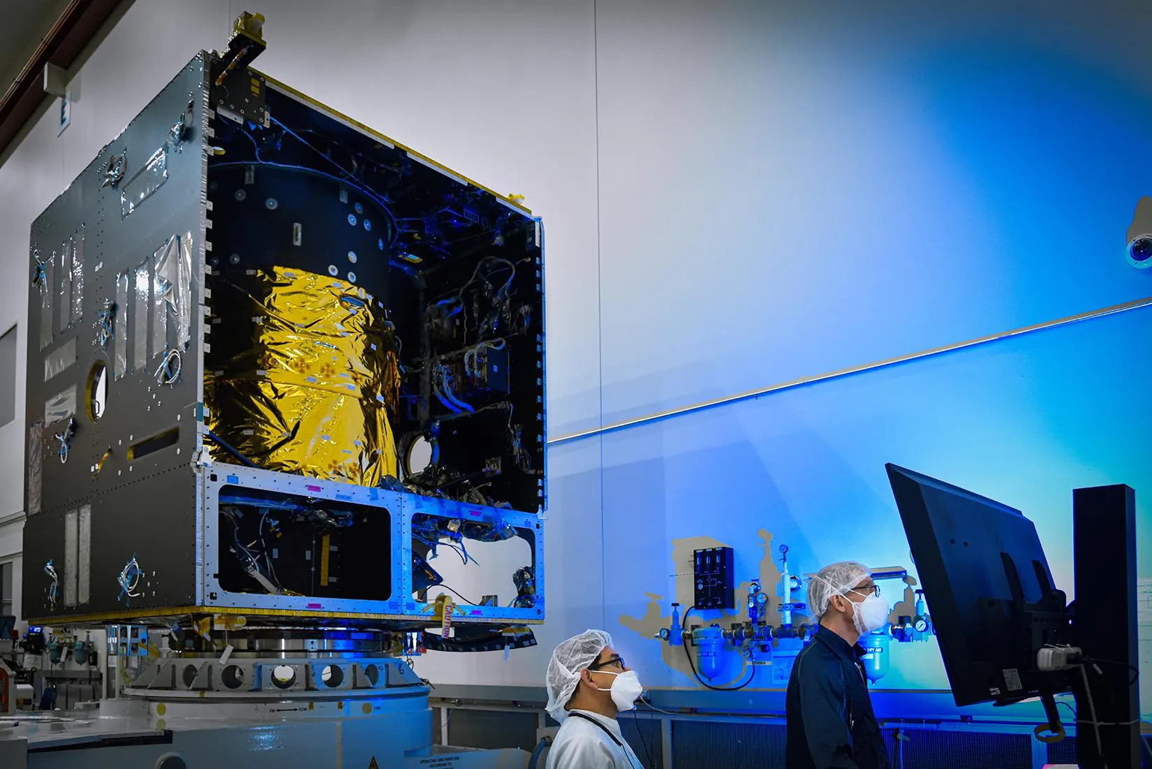 Engineers working around the main body of NASA's Psyche spacecraft